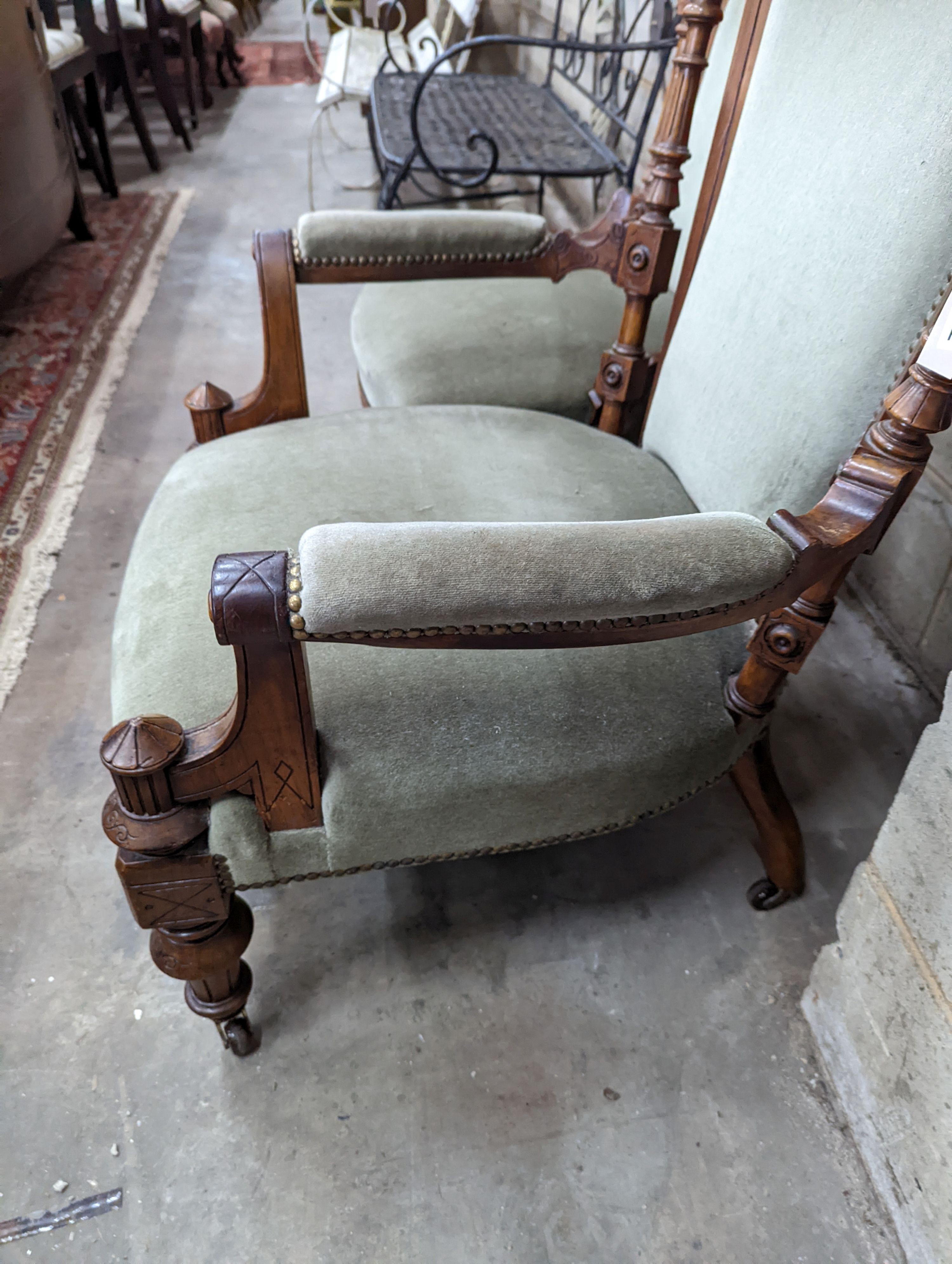 A pair of late Victorian carved walnut salon chairs upholstered in green dralon, one with arms